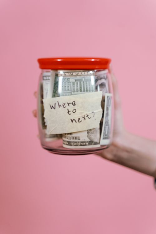 Free A jar filled with cash and a travel note against a pink backdrop symbolizing savings. Stock Photo