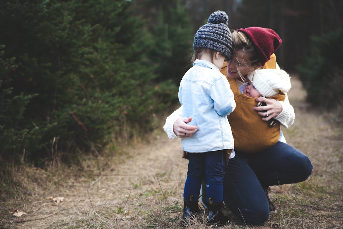 Free Woman With Brown Baby Carrier And Little Kid In White Jacket Stock Photo