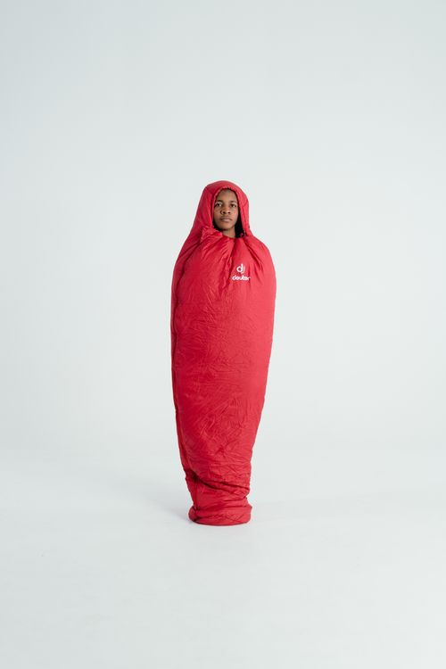 Free A person standing wrapped in a red sleeping bag against a plain background. Stock Photo