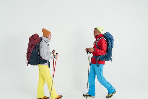 Free Man in Red Jacket with blue Backpack Standing beside Woman in Gray Jacket Stock Photo