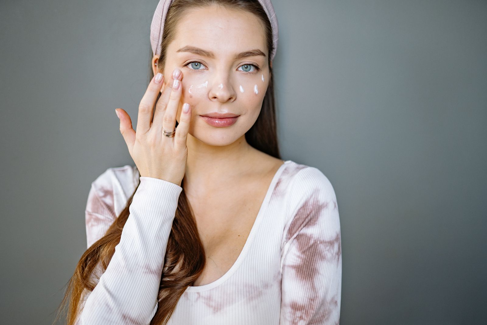 Young adult woman applying skincare before creating a dewy makeup finish