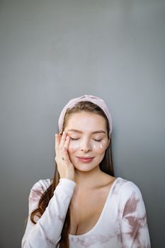 Caucasian woman enjoying skin care routine with cream on face and eyes closed, promoting self-care and beauty.