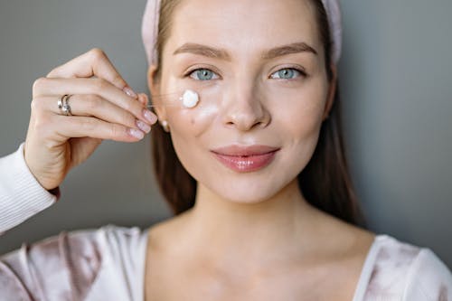 Close-Up Shot of Woman Applying Face Cream 