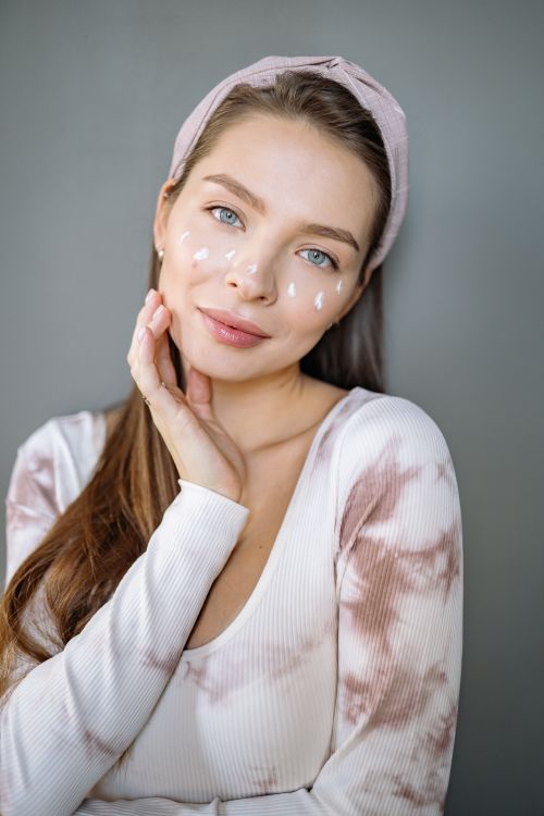Free Portrait of a woman with facial cream, wearing a headband in a serene setting. Stock Photo