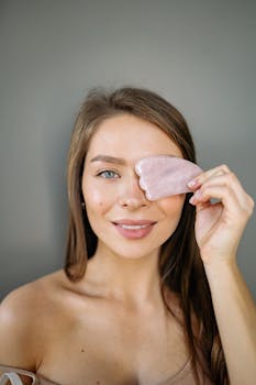 Smiling woman using a gua sha tool for skin care, highlighting natural beauty.