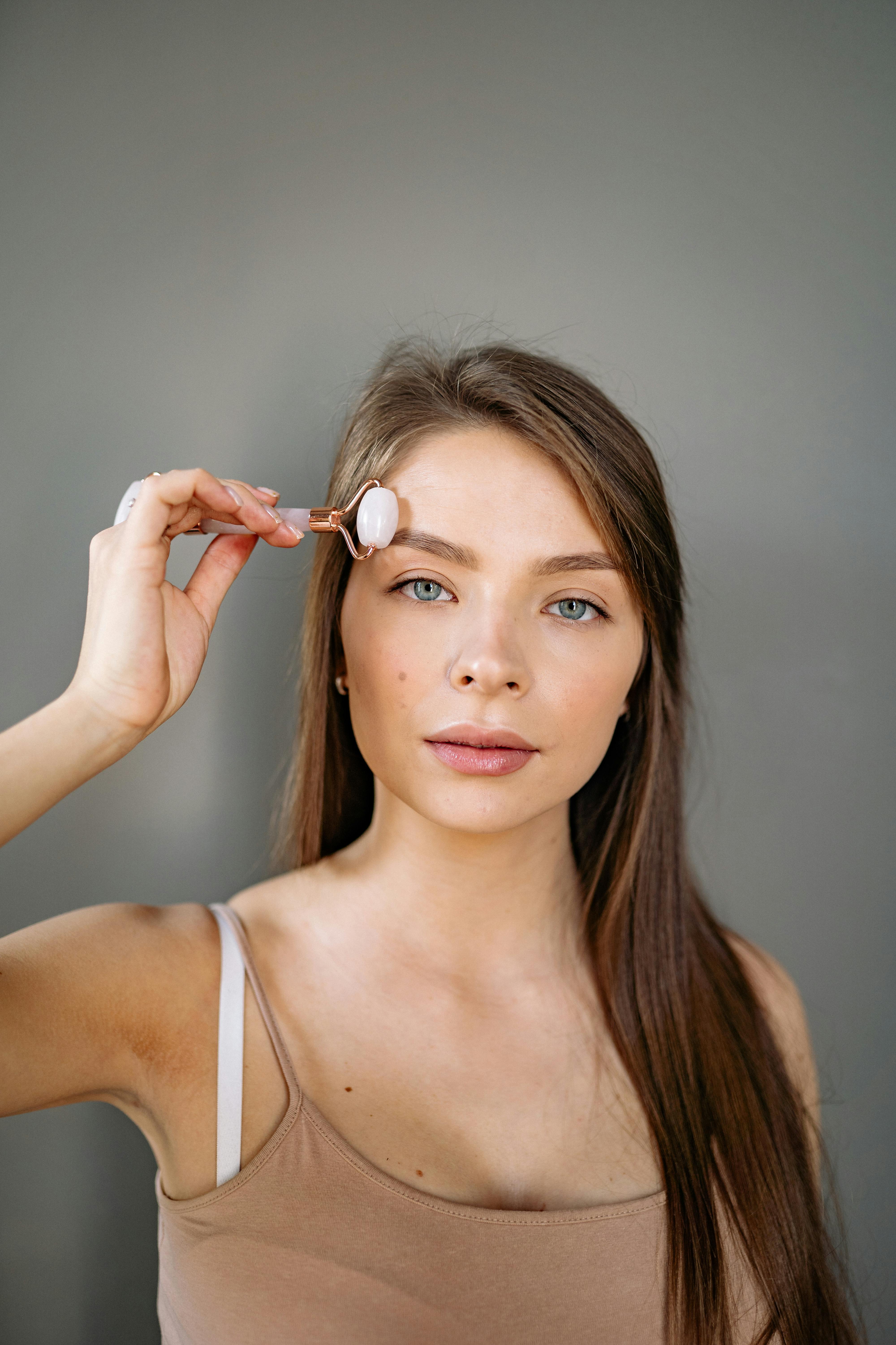 Young woman using a jade roller for facial self-care routine, promoting relaxation and beauty.