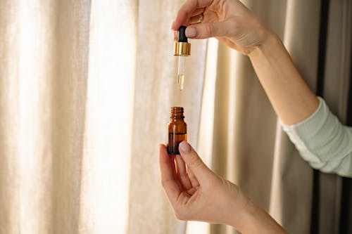 Free A Person Holding Amber Glass Dropper Bottle with Oil Stock Photo