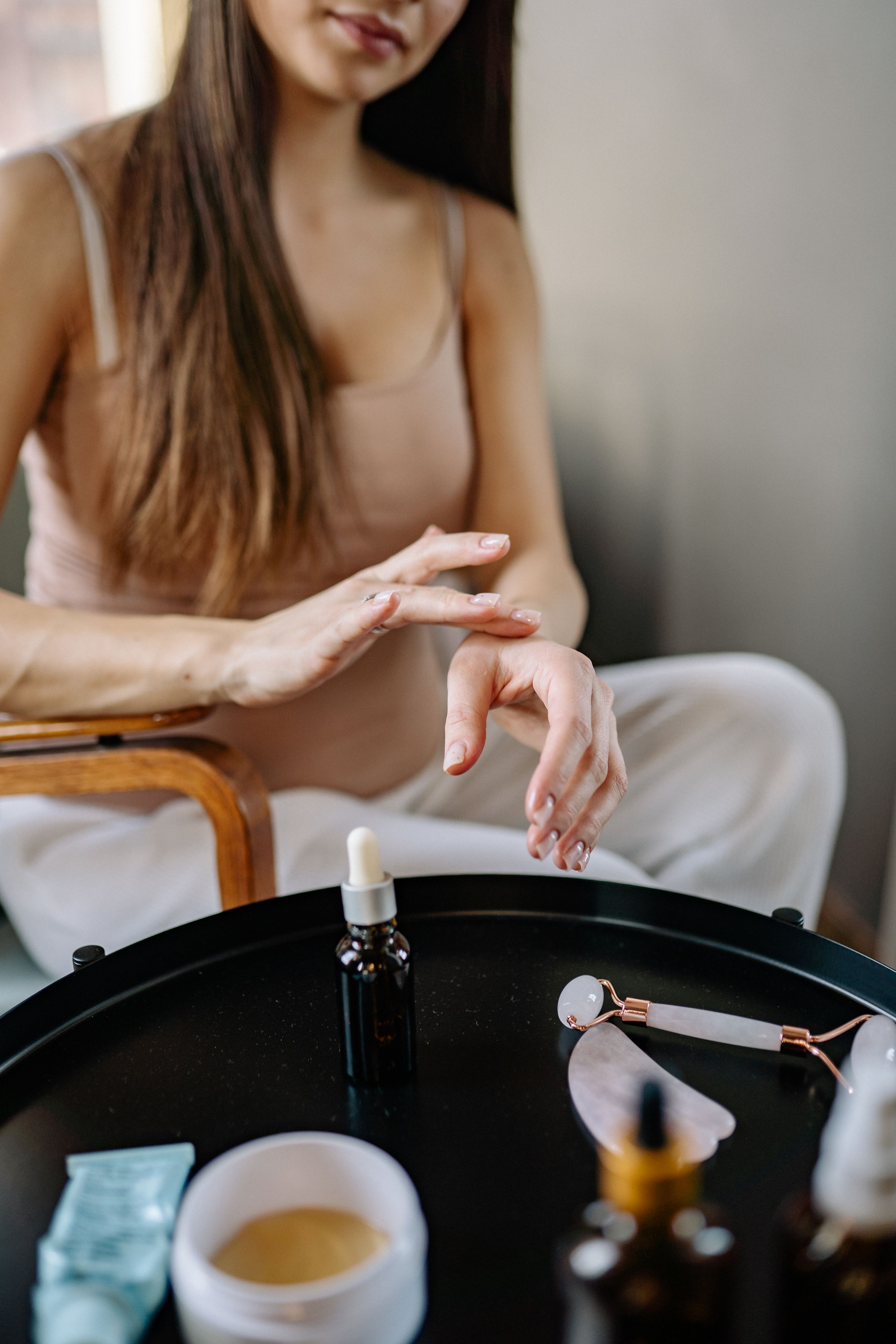 Uma mulher se entrega ao autocuidado com produtos de cuidados da pele e um rolo de jade em casa.