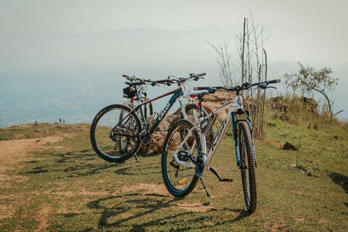 Free Two mountain bikes parked on a scenic hilltop path with a distant view of landscape. Stock Photo