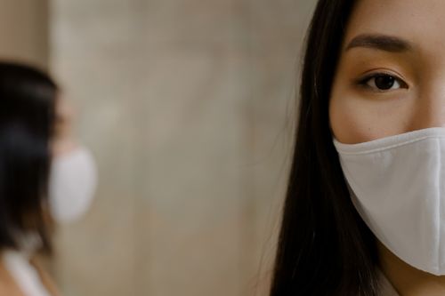 Free Close-up of an Asian woman wearing a face mask indoors during the pandemic. Stock Photo