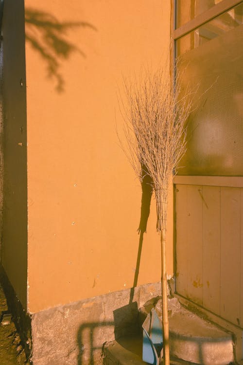 Бесплатное стоковое фото с вертикальный выстрел, желтая стена, метла