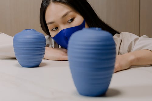 A Person Wearing Blue Face Mask Beside Blue Ceramic Pot