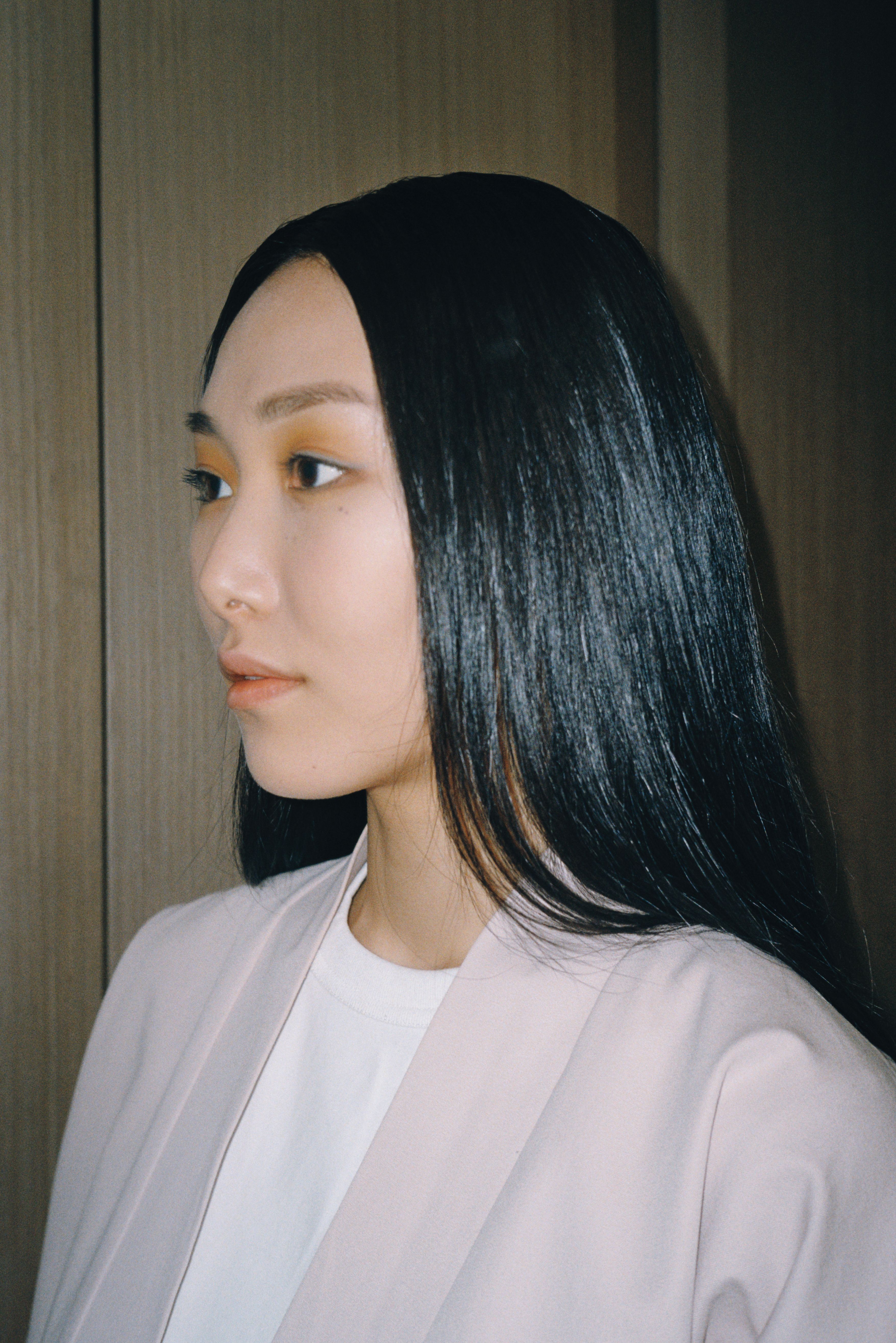 Side profile portrait of an Asian woman in a light coat, showcasing elegance and modern style.