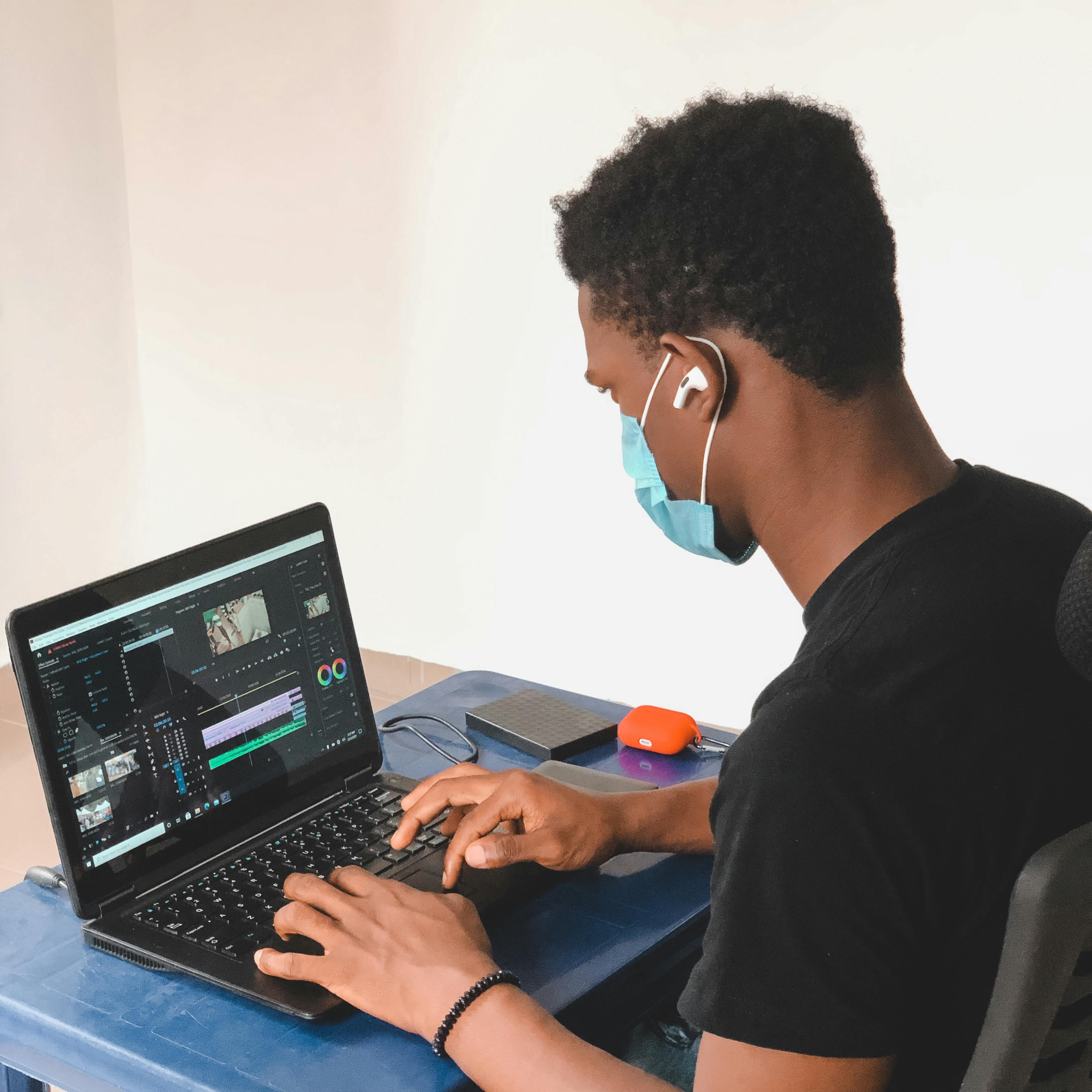 A Man Wearing a Facemask Using a Laptop