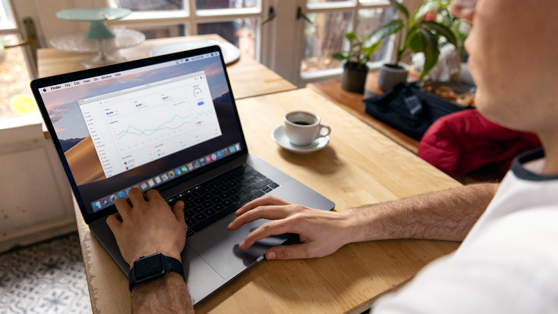 A person working on a laptop with business analytics displayed, showcasing a remote work setup in a cozy environment.