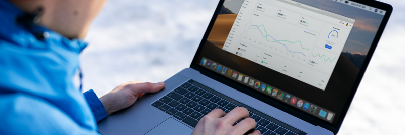 Person working on a laptop analyzing charts in an outdoor setting during winter.