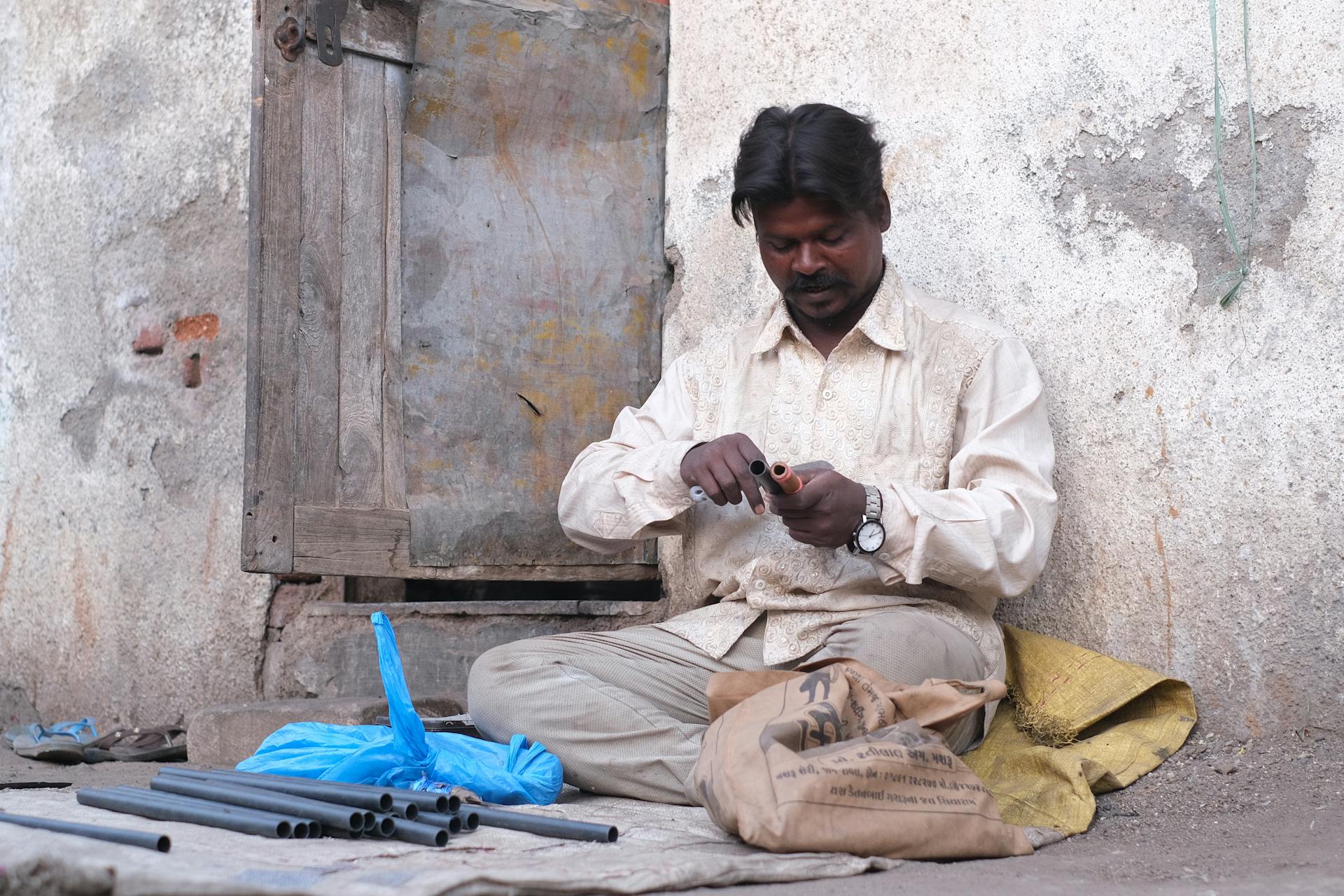 A middle-aged man works with pipes outdoors in Rajkot, India. Capturing local livelihood.