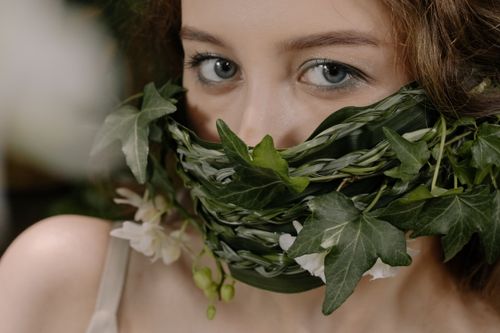 Free Close-up portrait of a woman wearing an ivy mask, blending nature and art. Stock Photo