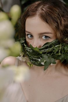 Artistic portrait with face covered by leaves, exploring nature's beauty.
