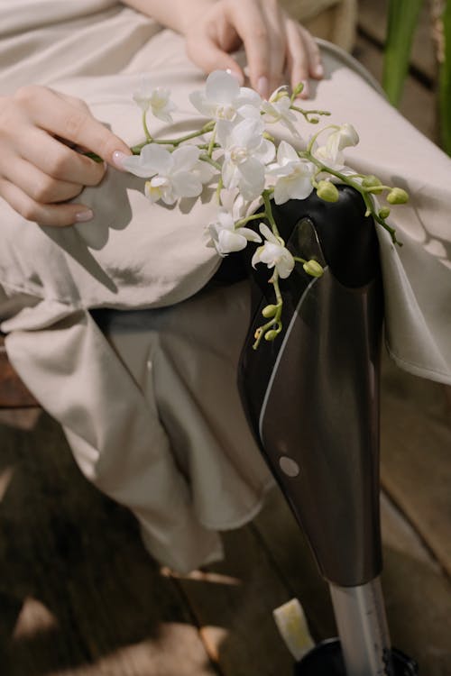 Disabled Person in Beige Dress holding White Flowers 