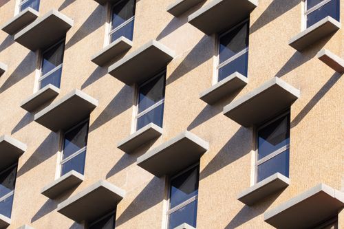 Free Close-up of a modern building facade with geometric window patterns and shadows. Stock Photo