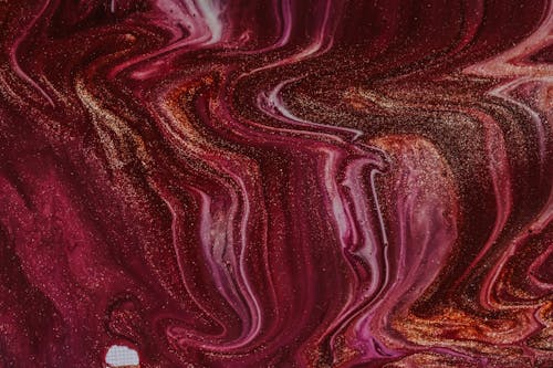 Top view of abstract background of mixed wet white and fuchsia paints with golden sequins spilled on surface