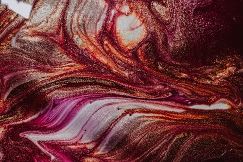 Free From above closeup of wet glossy surface of vivid pink golden and white paints mixing and forming abstract curves Stock Photo
