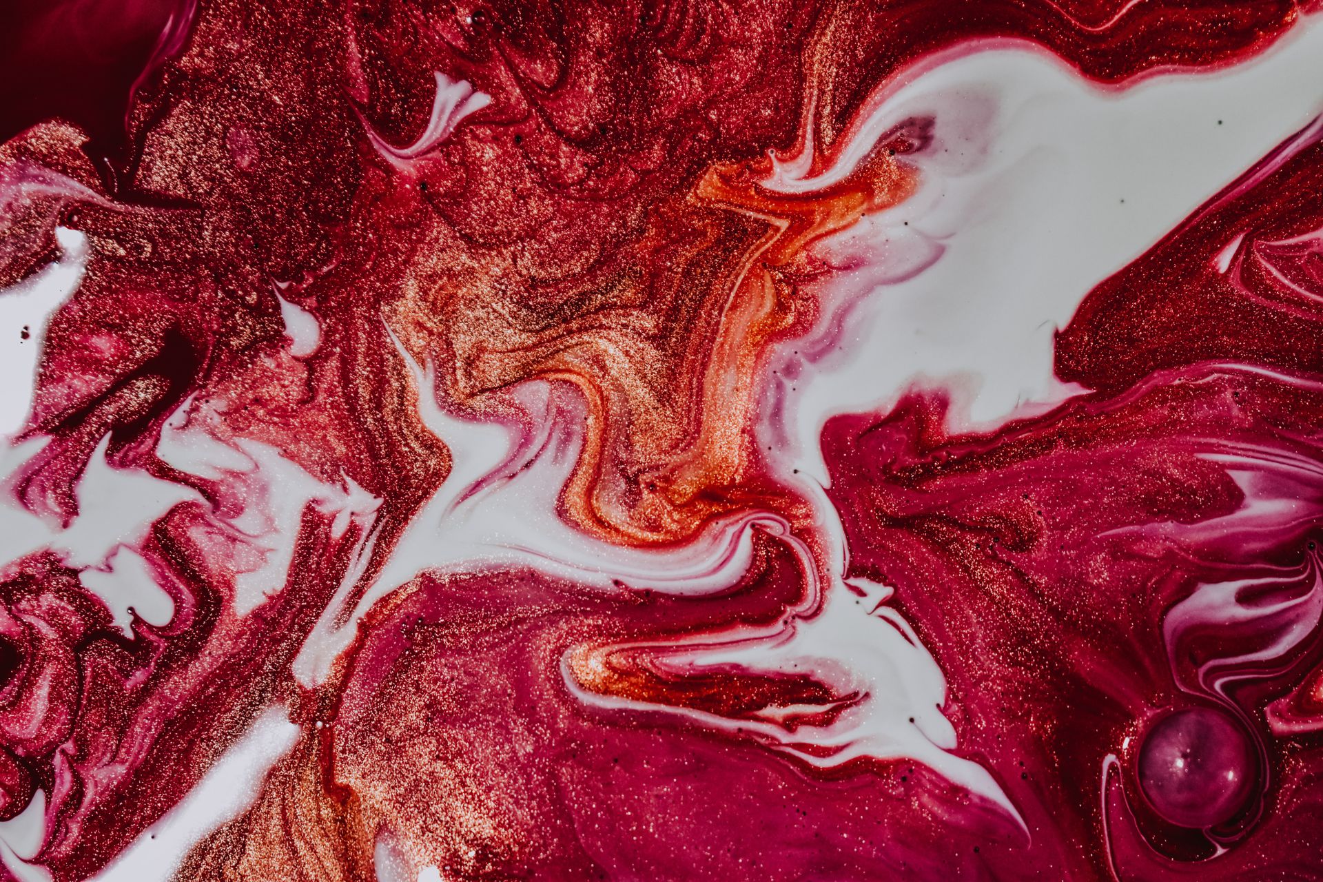 Mix of vivid fuchsia and white paints with golden glitters as background