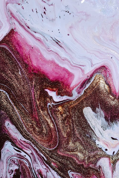 From above of bronze shimmering acrylic paint and mixing with white and pink dyes and forming abstract background