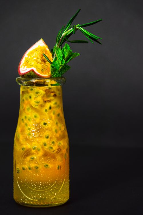 Free A vibrant passion fruit cocktail garnished with fresh mint and rosemary, perfect for summer refreshment. Stock Photo