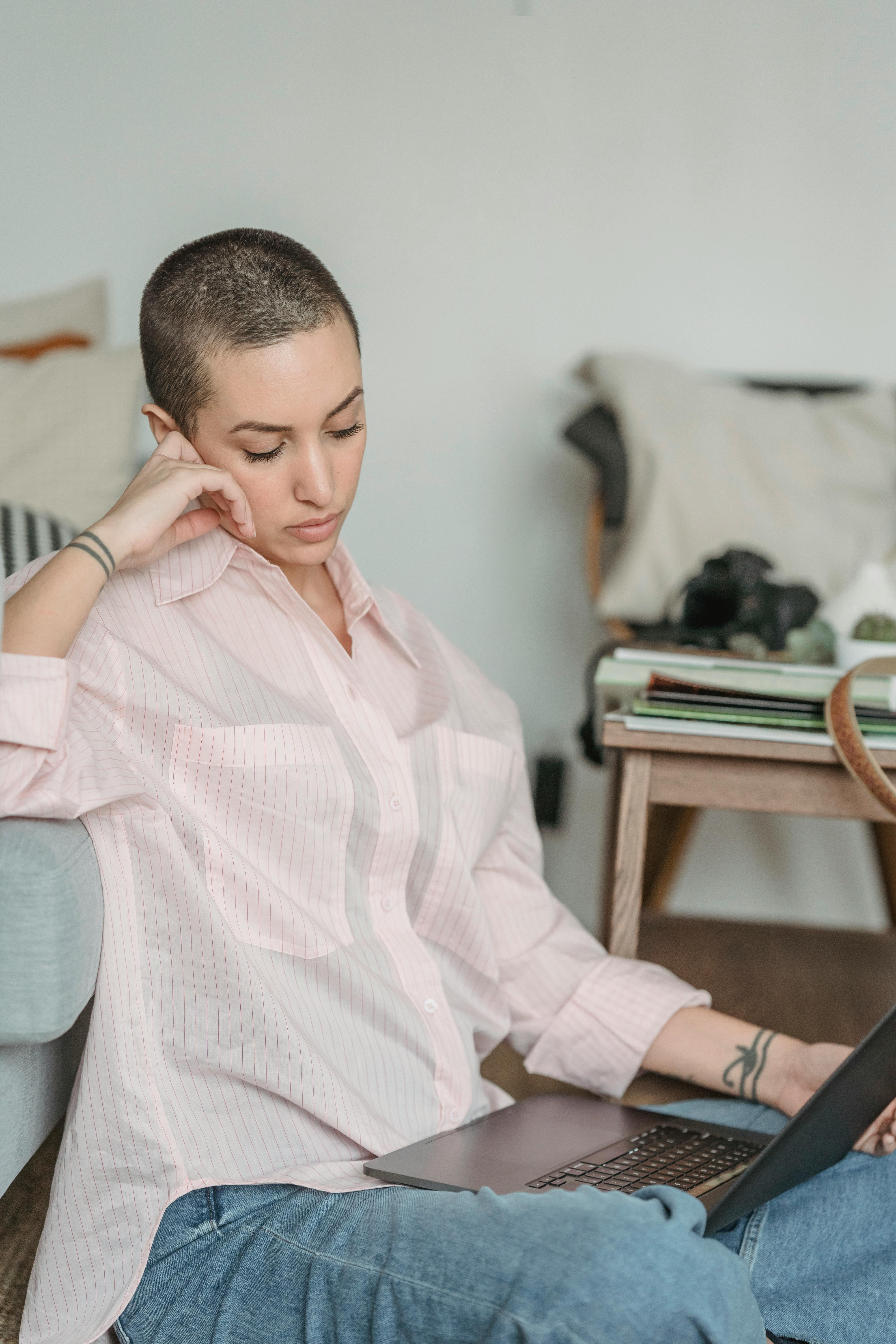 pensive young female freelancer working online on netbook sitting on floor near coach