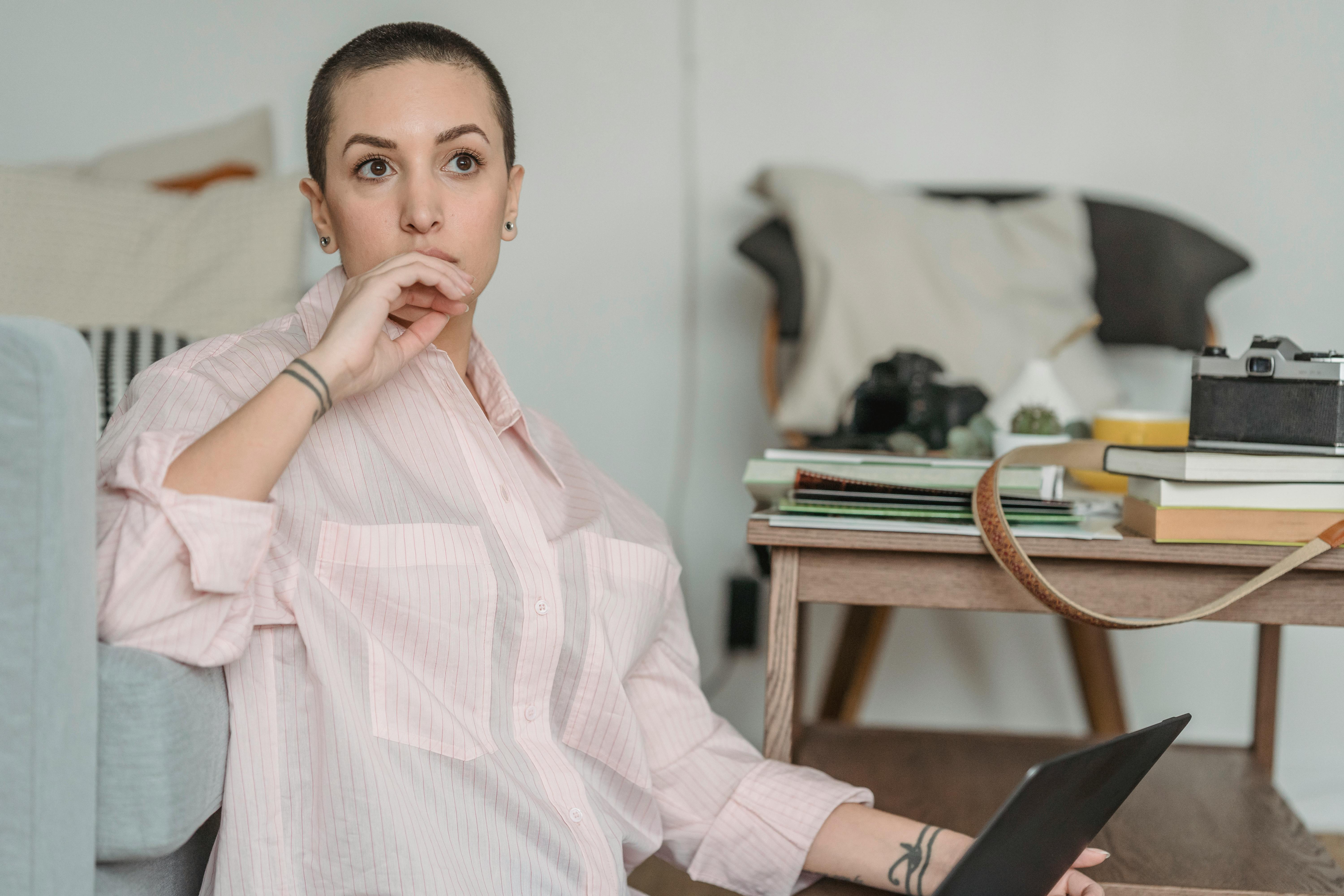 thoughtful young self employed woman looking away during work on netbook at home