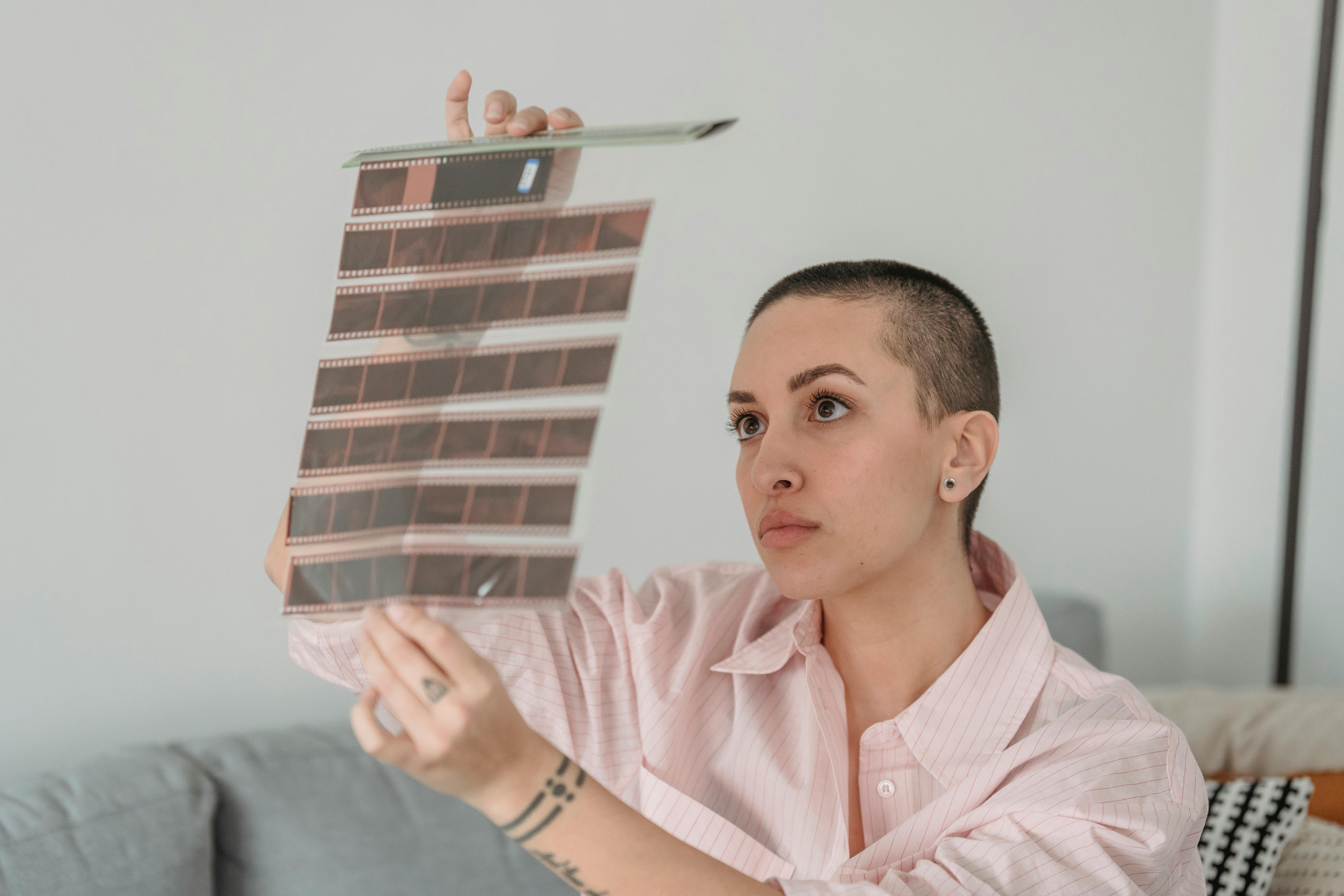 serious young lady looking at filmstrips sitting on couch at home