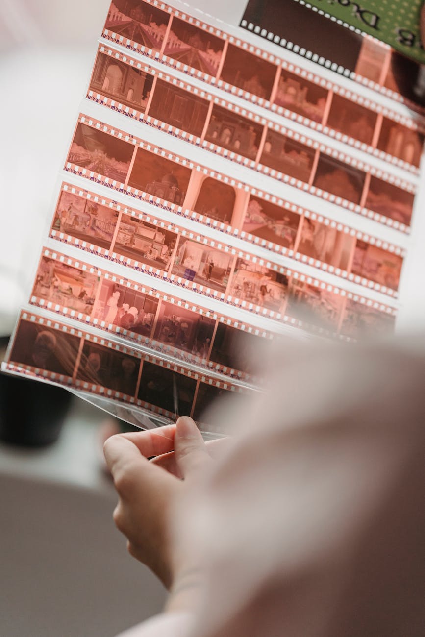 Close-up of hands examining film negatives, showcasing analog photography nostalgia.