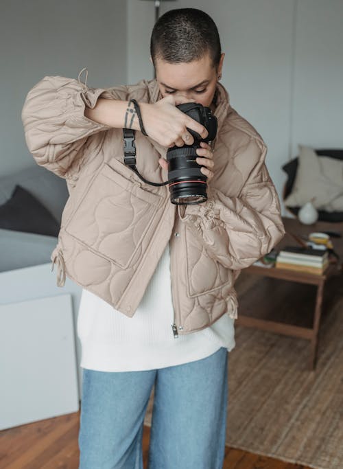 Photo of a Woman in a Beige Jacket Using a Camera