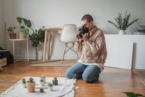 Photo of a Woman in a Beige Jacket Taking a Photo of Plants