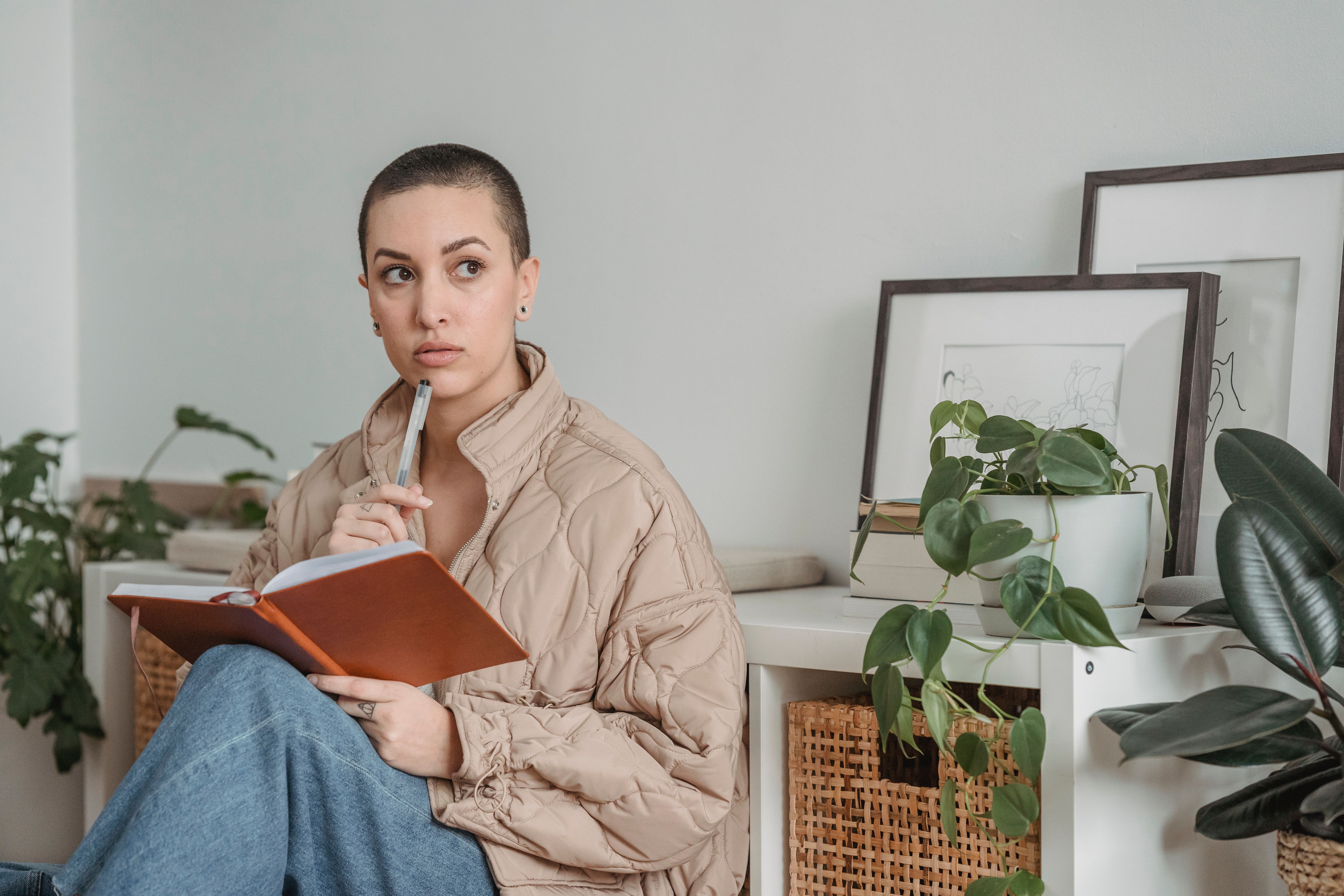 A person sitting in a church pew, holding a journal and pen, looking thoughtful and peaceful