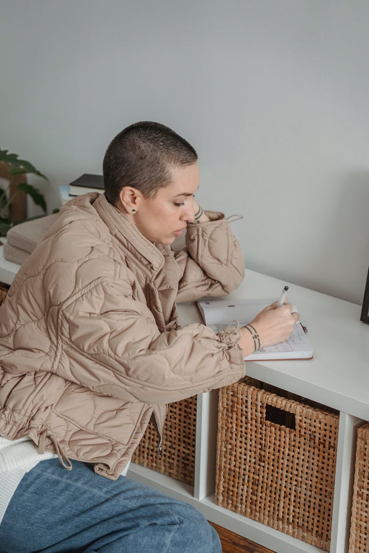 Thoughtful Woman Writing In Notebook At Home