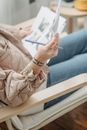Crop illustrator with papers in armchair at home