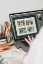 Crop unrecognizable female freelancer using touchpad while retouching photos on laptop during remote work at home