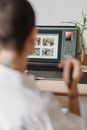 Crop faceless photographer browsing laptop and choosing photos