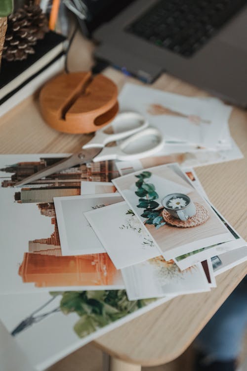 From above of various images scattered on wooden table near netbook for remote work from home