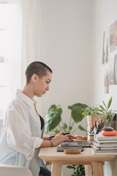 Young woman concentrating on her laptop in a bright, cozy home office setting.