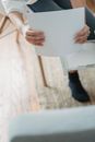 From above of crop anonymous female remote worker sitting on chair and preparing paper for printing document