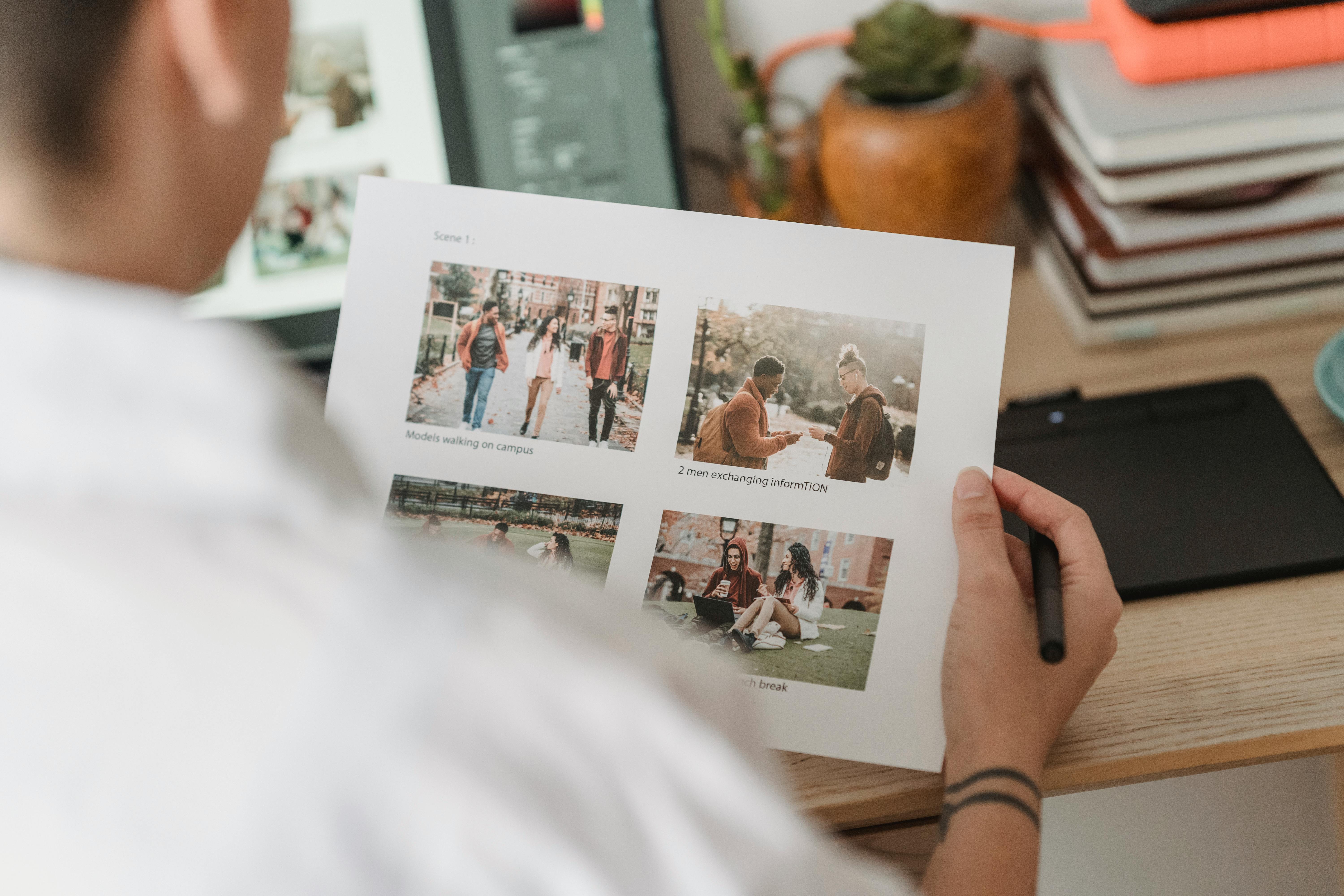 woman with printed photos sitting at table with laptop