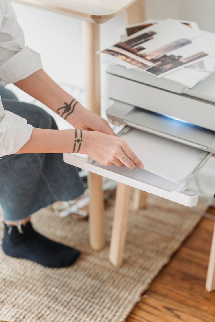 Woman Placing Paper In Printer For Making Photos