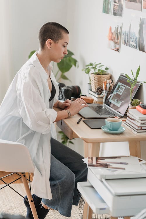 Free Young woman doing remote work on laptop Stock Photo