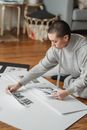 Young female with short hair compiling photography collage on blank paper sheet in house room