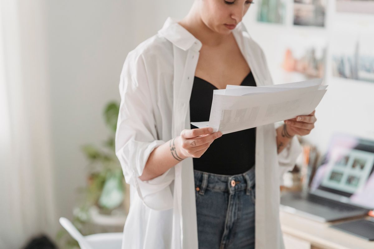 A young professional reviewing paperwork on a laptop at home