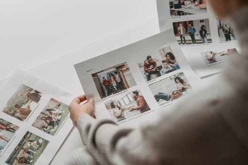 Free From above of crop unrecognizable person preparing to create collage of photos of multiracial friends on paper sheets Stock Photo